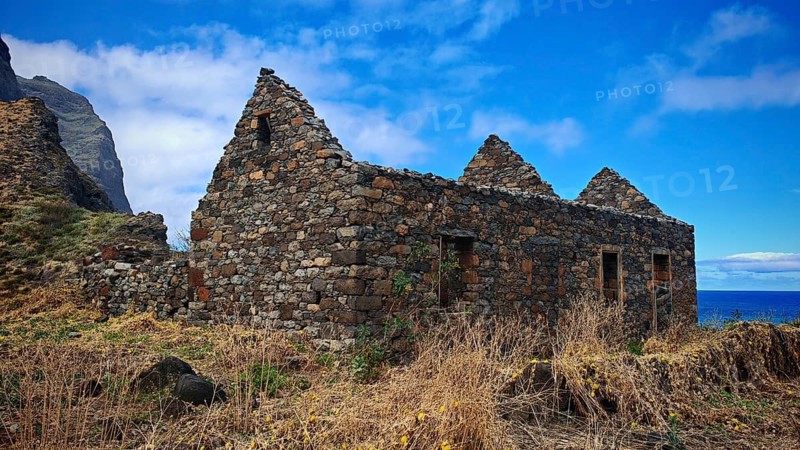 Abandoned stone houses, volcanic stone ruins nestled naturally in beautiful countryside with sea views and blue skies, hiking, lost place, abandoned village of Formiguinhas, Marinha da Cruzinha Natural Park, Santo Antao, Cabo Verde, Cape Verde, Cape Verde