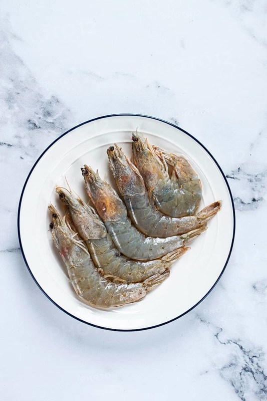 Fresh raw white-footed shrimp, tiger prawns vannamei, on a white plate