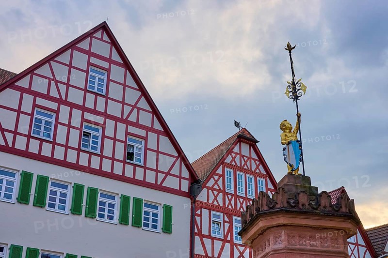 Half-timbered houses with a gilded statue, green shutters against a blue sky, Marktbrunnen, Marktbornskindchen, spa town of Bad Orb, Spessart nature park Park, Main Kinzig district, Hesse, Germany