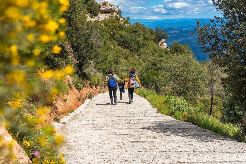 Family walking down a path in montserrat mountains, enjoying the scenic view and the natural landscape