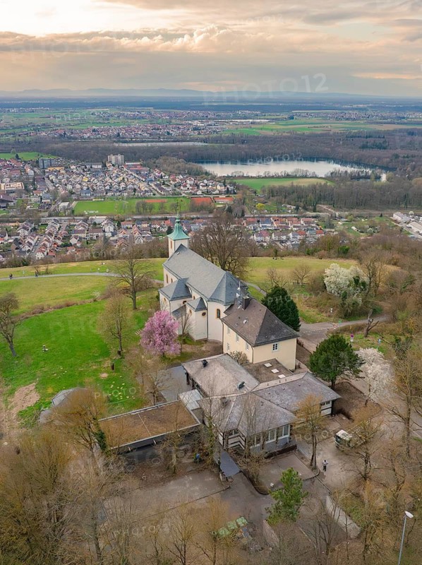 View of a church and village from above, embedded in a green landscape with a cloudy sky, Michelsberg, Bad Münstereifel