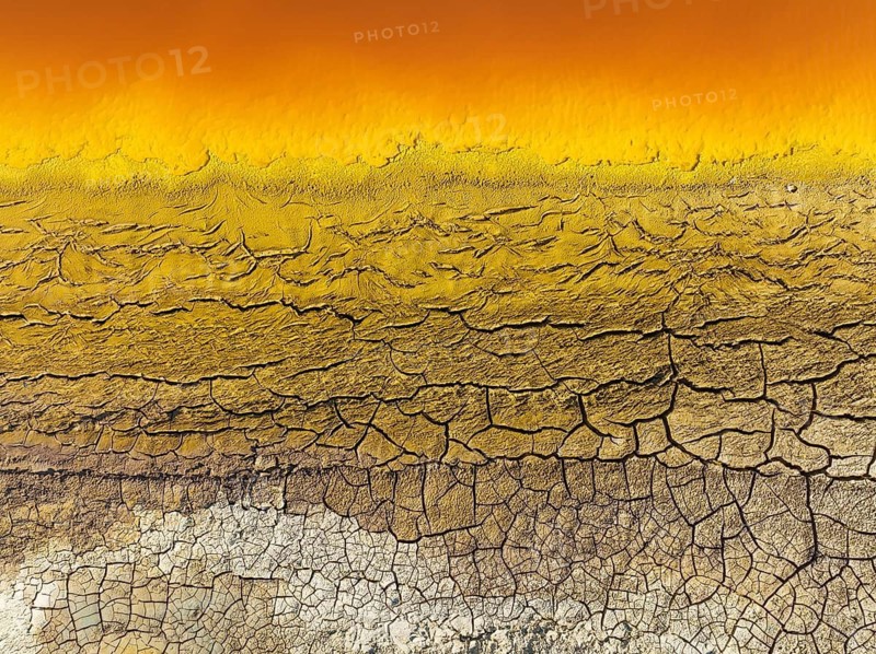 Cracked earth at the bank of the Rio Tinto (Red river) with its deep reddish hue due to oxidised iron minerals in its water, aerial view, drone shot, Huelva province, Andalusia, Spain