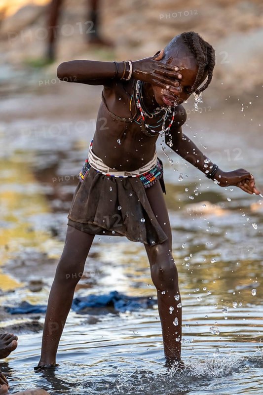 Himba child washing with water on a river, traditional Himba, Kaokoveld, Kunene, Namibia