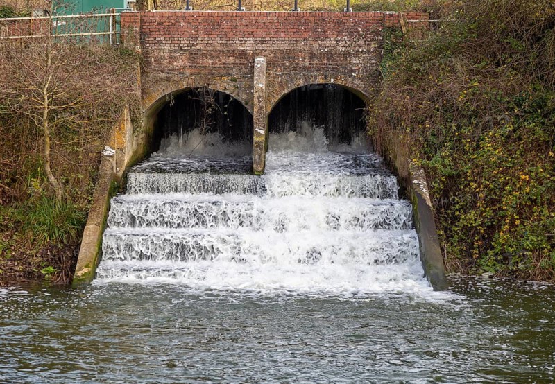 Bridge and weir with rushing water on River Marden, Bremhill, Calne, Wiltshire, England, UK
