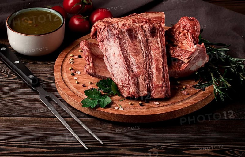 Smoked pork ribs, on a wooden table, top view, sauce, tomatoes and spices, close-up, vertical, no people