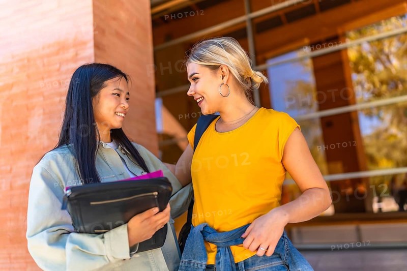 Happy female multi-ethnic university students talking outside the university building