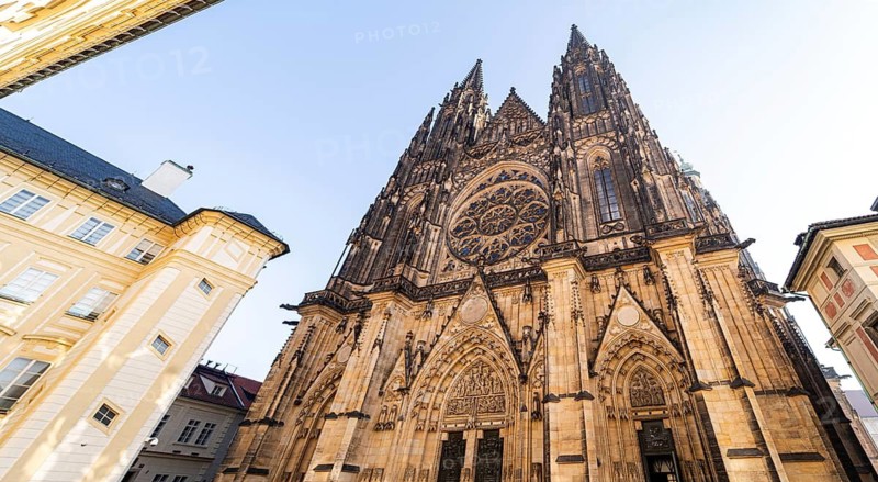 A view of a stunning Gothic cathedral in Prague, showcasing intricate details, towering spires, and historical charm under a clear sky, embodying rich architectural heritage