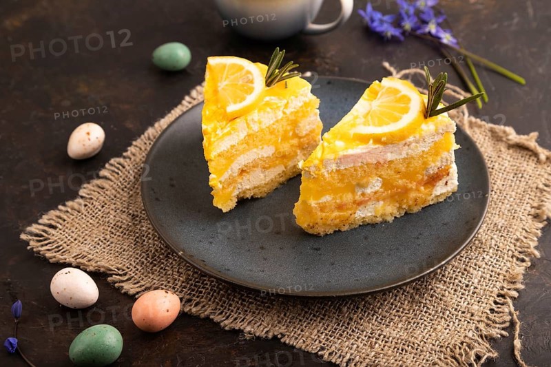 Lemon cake on black concrete background and linen textile, cup of coffee, side view, close up
