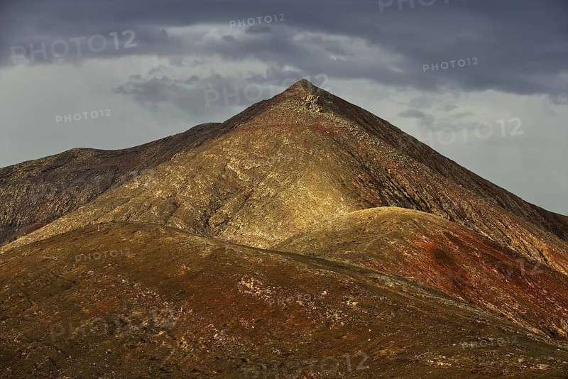 Dramatic view of a steep, brown mountain peak under a cloudy sky, Pajara, Fuerteventura, Canary Islands, Spain