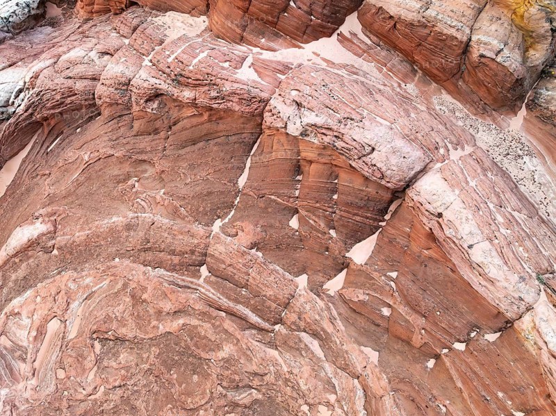 Captivating aerial view of textured red desert landscape, showcasing intricate layers and natural patterns in the rocky formations, highlighting the earth's raw beauty and geological history