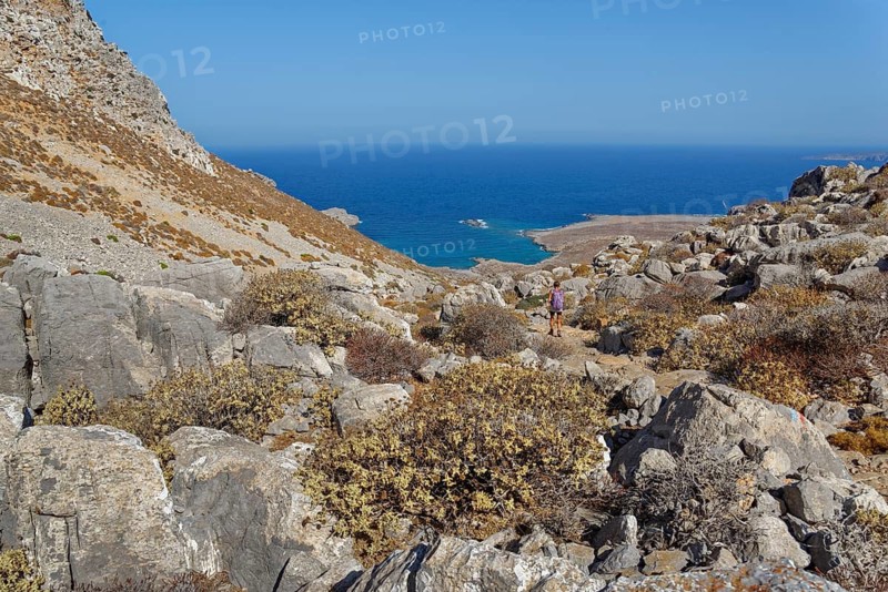View of a rocky coastal landscape with blue sea, hike to the ancient Dorian city of Vrougounda and the cave church of St John Vrykountas, Avlona, Karpathos, Greece