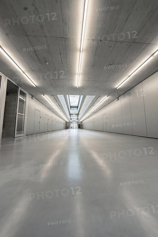 An elongated, well-lit corridor with concrete walls showing central elements of modern, minimalist architecture, University of Stuttgart, Germany