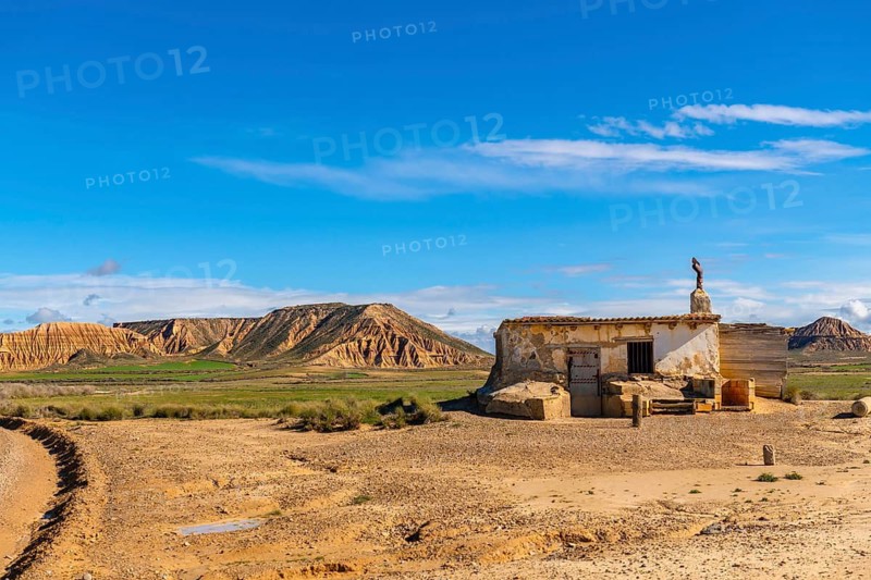 Old abandoned building standing in the arid landscape of bardenas reales desert in navarre, spain, under a vibrant blue sky