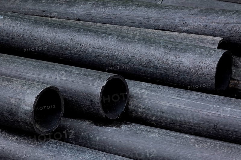 Close-up of stacked long black ABS plastic drainage pipes in storage yard, Quebec, Canada