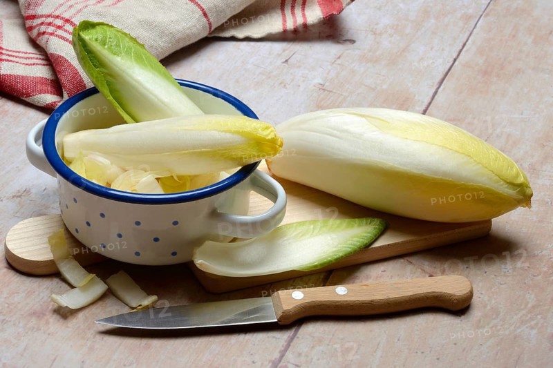 Chicory, chicory salad on wooden board with knife