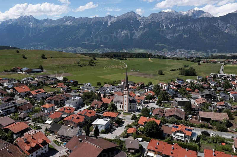 Drone shot, view of village with parish church and Karwendel mountains, Rinn, Tyrol, Austria