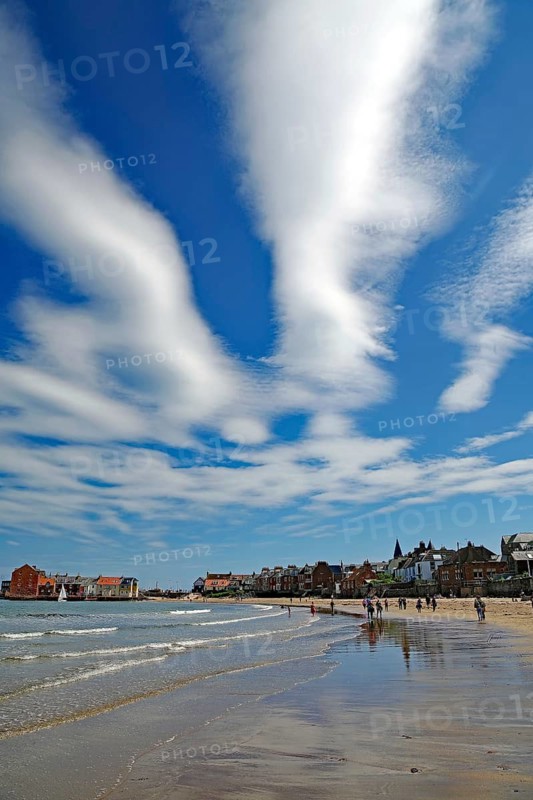 Sandy beach beach with impressive clouds and blue sky, surrounded by coastal buildings and people, North Berwick, Scotland, United Kingdom