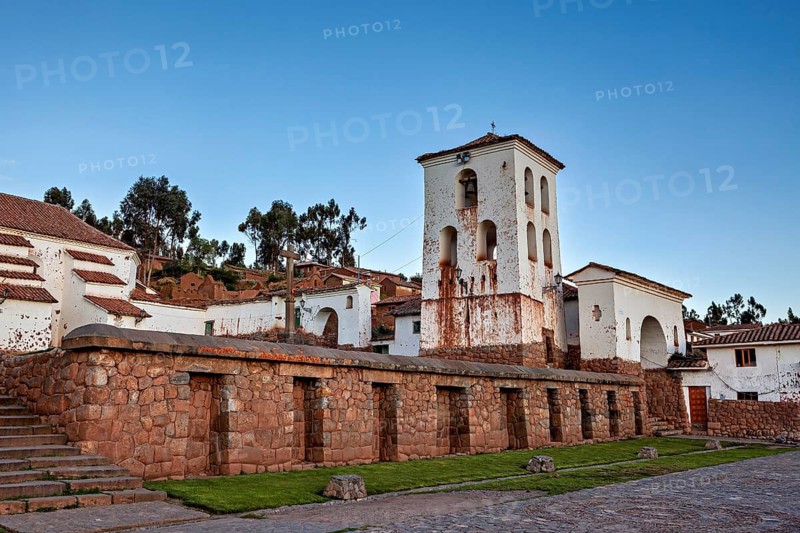 Colonial church tower and buildings with stone walls surrounded by nature in daylight, the historic village of Chinchero in the Sacred Valley of the Incas in Peru