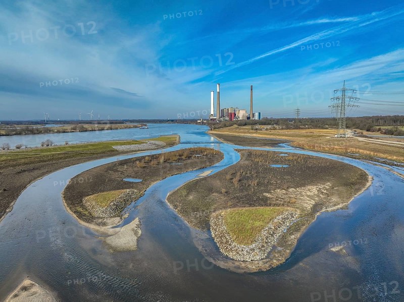 Dinslaken, Voerde, North Rhine-Westphalia, Germany - New Emscher estuary into the Rhine. Renaturalisation of the Emscher. Flood protection through land expansion. The decommissioned STEAG Voerde coal-fired power station in the background. The mouth of the Emscher into the Rhine was moved almost 500 metres north from Dinslaken to Voerde. Fish can now swim barrier-free up the new Emscher from the Rhine through a newly created floodplain area. Following the construction of a parallel sewer, the Emscher has been completely free of sewage since January 2022. The river was previously an open, above-ground combined sewer with rainwater and wastewater
