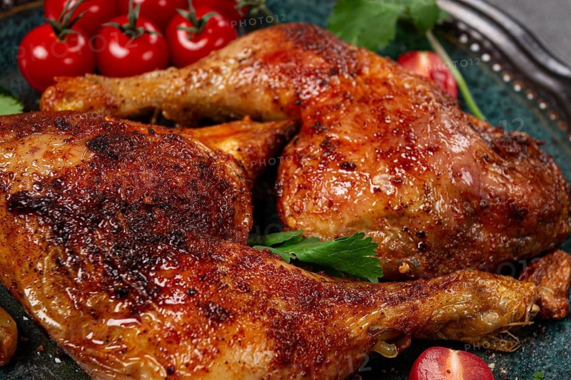 Grilled fried chicken legs, served with fresh cherry tomatoes and herbs, on a plate, homemade, no people