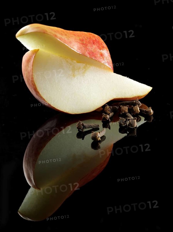 2 pear quarters, cloves, fruit and vegetable decoration on black background, studio shot
