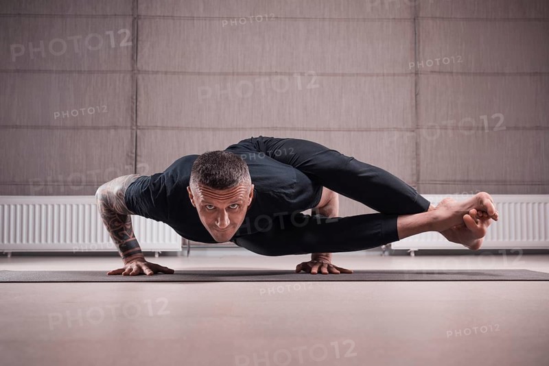 Adult man performs asana exercises. Yoga concept. Sports and healthy lifestyle.