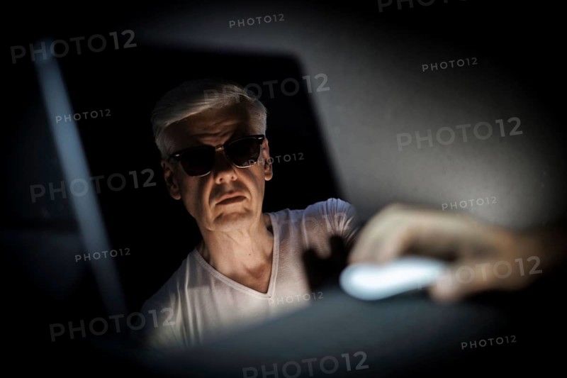 Topic: Cybercrime. A face with sunglasses is reflected in a screen in Berlin, 09/08/2024