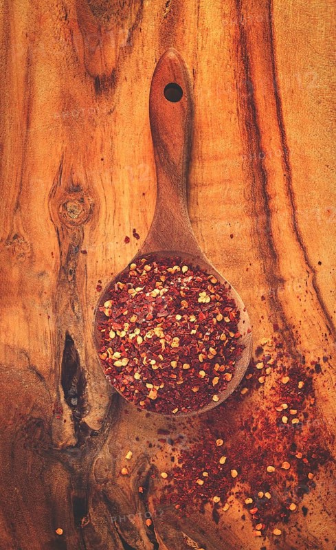 Red pepper flakes, in a wooden spoon, on a wooden table, rustic style, no people