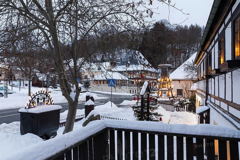 Twilight view of Hammerherrenhaus and village pyramid in snow, Frohnauer Hammer, Annaberg-Buchholz, Ore Mountains, Saxony, Germany