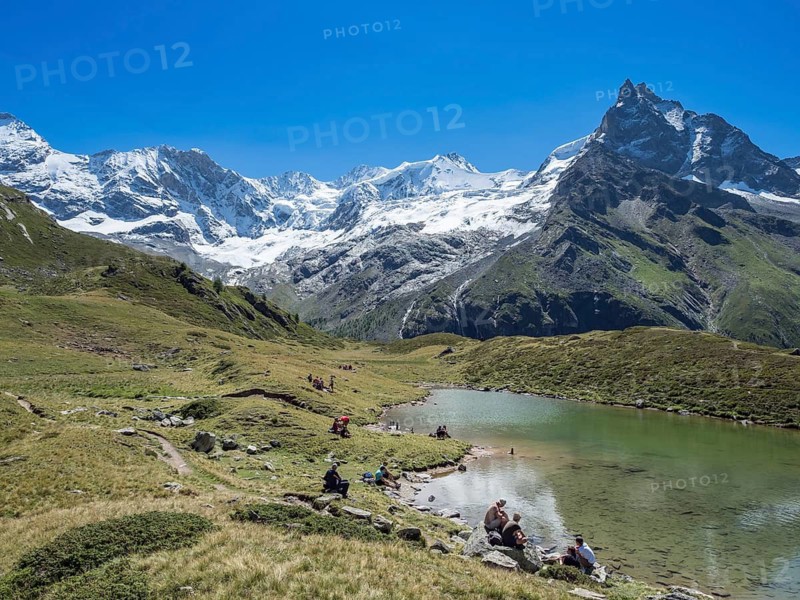 HIkers take a break at lake Lac d'Arpitetta, Zinal valley, Val d'Anniviers, Switzerland