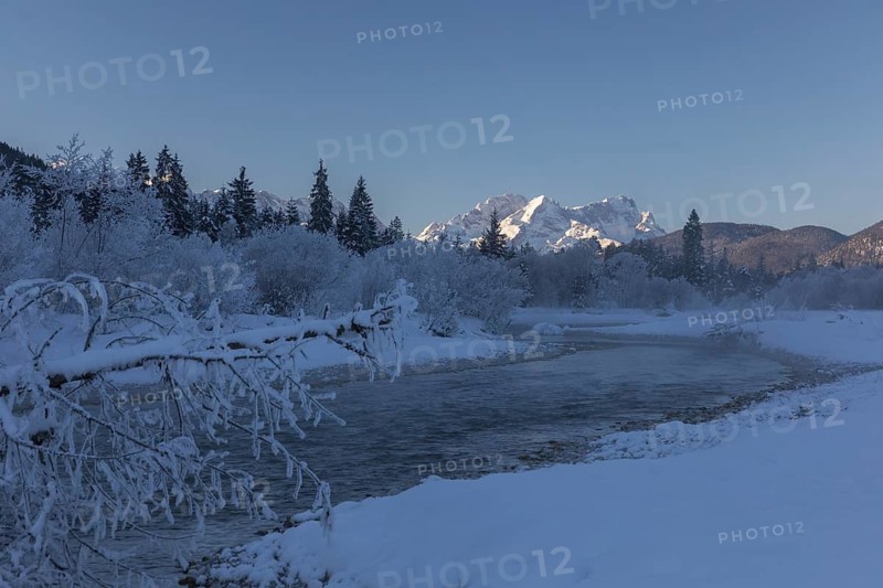 Isar valley in winter at temperatures of minus 18 degrees Celsius. Snow covered landscape with the Isar river flowing through. Some hoar frosted trees. Early morning at sunrise