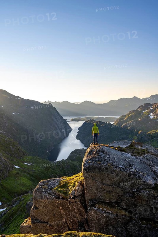 Mountaineer, young man in front of mountain landscape at sunrise, fjord Trollfjord and Raftsund, hike to Trollfjord Hytta, Lofoten, Nordland, Norway