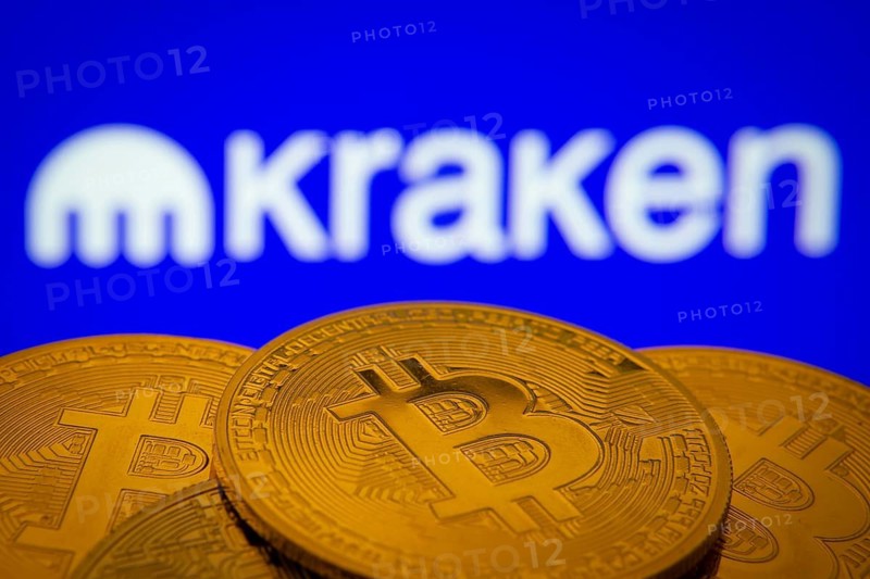 Dhaka, Bangladesh- 01 Nov 2025: Close-up of Bitcoin coins with the Kraken logo visible on a screen in the background