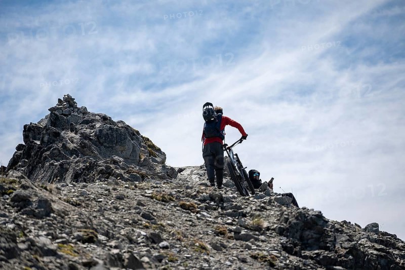 Mountain biker pushes his mountain bike to the rocky summit of Cerro Goye in the Patagonian Andes near Bariloche, Argentina