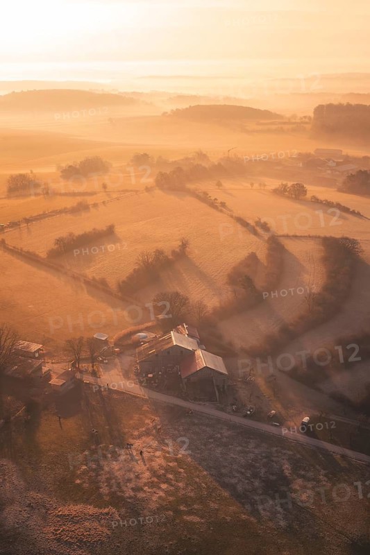 Aerial view of a farmhouse and fields in golden morning fog, Gechingen, Calw district, Germany