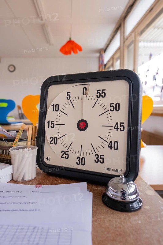 Timer and table bell on a table full of papers in a bright classroom, homework supervision, Schlehengäu Grund Schule Gechingen, Calw district, Germany