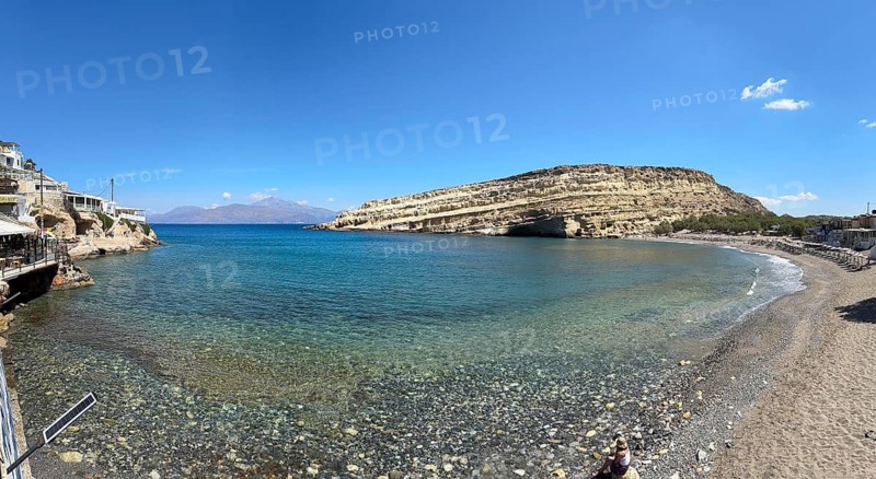 View of bay and beach of Matala with Libyan Sea Mediterranean on south coast of island Crete, in the background sandstone cliffs with former Roman necropolis in 60s 70s of 20th century hippie caves sandstone caves retreat of for dropouts, Matala, Crete, Greece