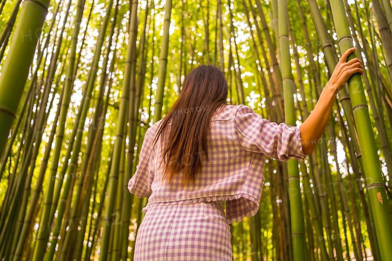 Young caucasian girl with a pink skirt in a bamboo forest. Enjoying the summer holidays in a tropical climate, strolling back in the forest