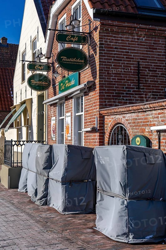 The fishing village of Greetsiel, municipality of Krummhörn, historic houses at the fishing harbour, restaurant during winter break, wrapped beach chairs, in winter, Lower Saxony, Germany