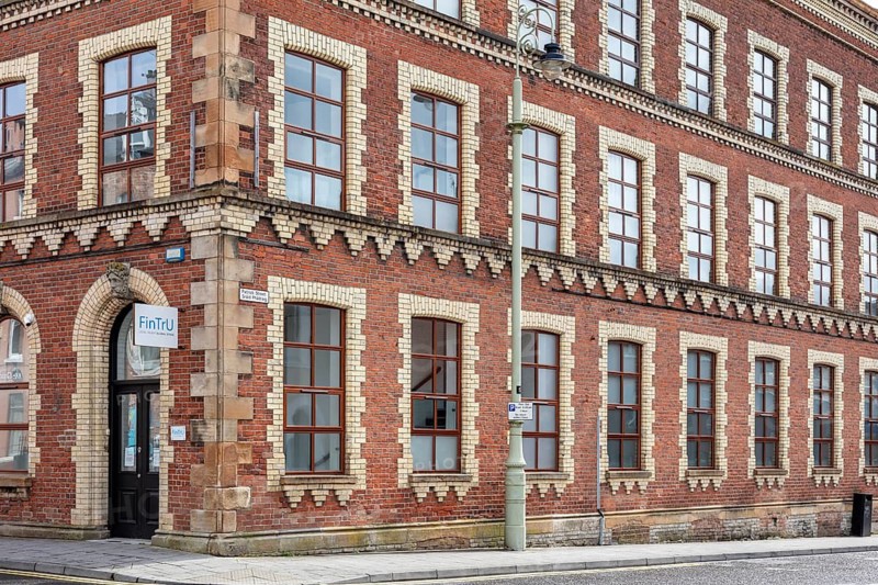 Large historic brick building on a corner with numerous windows and a red façade, Letterkenny