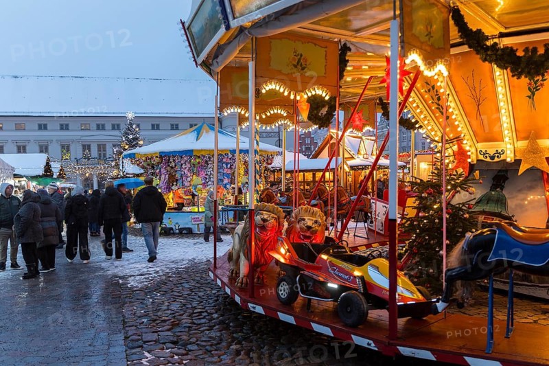 Children's carousel at the snowy Christmas market on the market square of the Hanseatic city of Wismar, in the background the town hall, Mecklenburg-Vorpommern, Germany