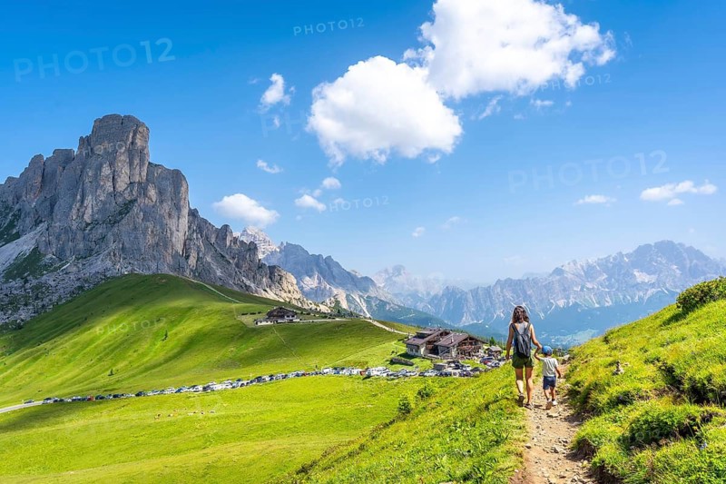 Mother and son walking on a path at giau pass enjoying the beautiful landscape of the dolomites in summer