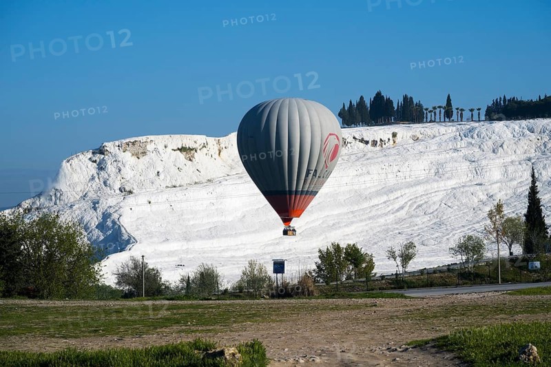 A hot air balloon floats in front of white limestone terraces and a blue sky, sinter terraces, lime sinter terraces, travertine terraces, Pamukkale, Denizli, UNESCO World Heritage Site, Anatolia, Turkey