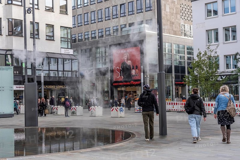 Digital water feature, Blue Cloud water installation on Husemanplatz in downtown Bochum, water mist is sprayed from 4 metal masts, which, in conjunction with the circular water surface, is intended to cool the surrounding area when it is hot, colored light images are projected into the water mist via projectors, part of the transformation of Husemanplatz