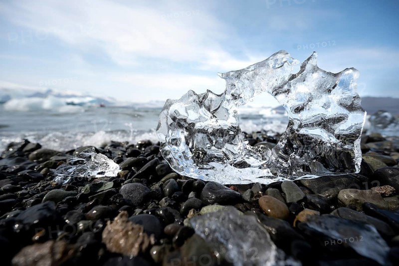 Ice, piece of ice with hole on black gravel beach, glacier lagoon Jökulsárlón, glacial lake, southern edge of Vatnajökull, southeast Iceland, Iceland