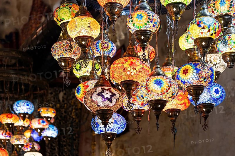 Vibrant handmade lamps hanging in a market in Jerusalem, near historical religious landmarks in the old city, showcasing intricate glass work