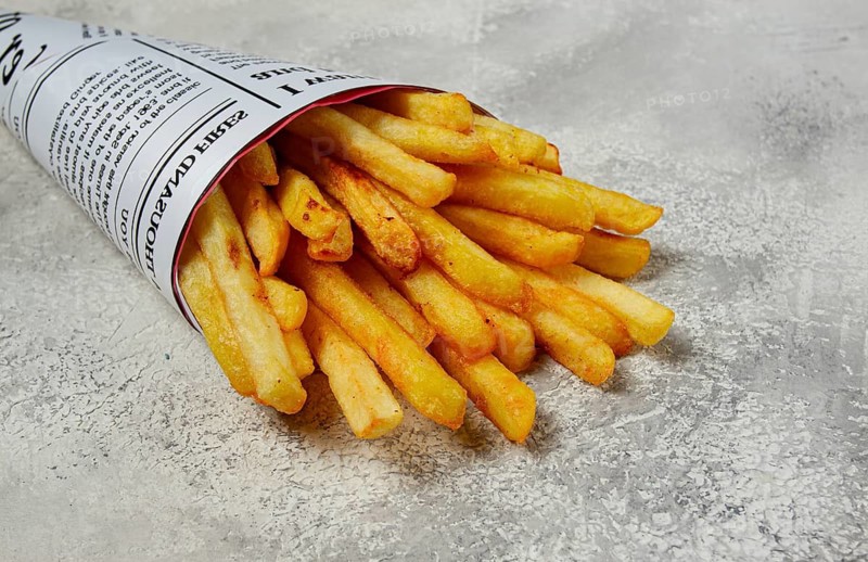Fried French fries in a paper bag, on an abstract background, without people, in a rustic style, in a cone package, newspaper, a bag from the newspaper