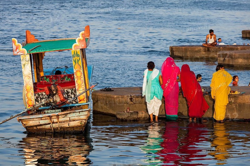 MAHESHWAR, INDIA, APRIL 26, 2011: Indian women doing morning pooja on ghats of sacred Narmada river. Maheshwar, Madhya Pradesh, India