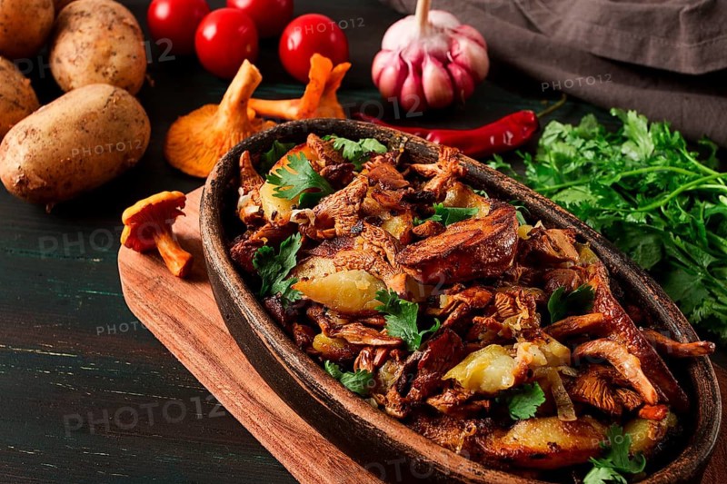 Fried chanterelles with mushrooms, in a clay pan, close-up, top view, selective focus