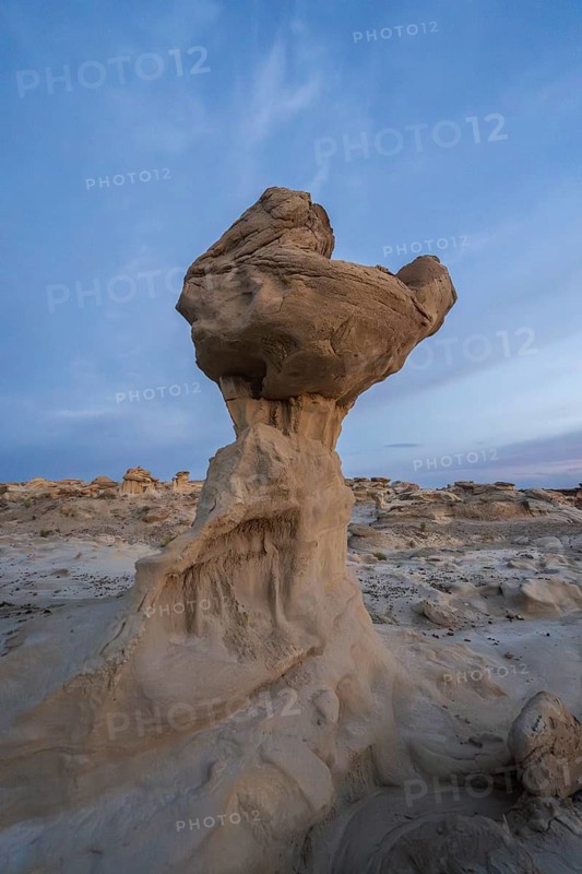 Sandstone formations in Bisti De-Na-Zin Wilderness, New Mexico, USA, showcase dramatic erosion against a dusky sky, reflecting millennia of geological history